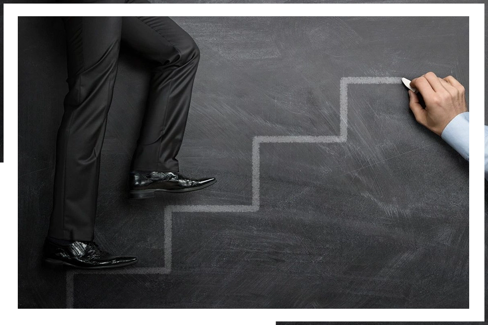 A man in black suit and shoes standing on stairs.